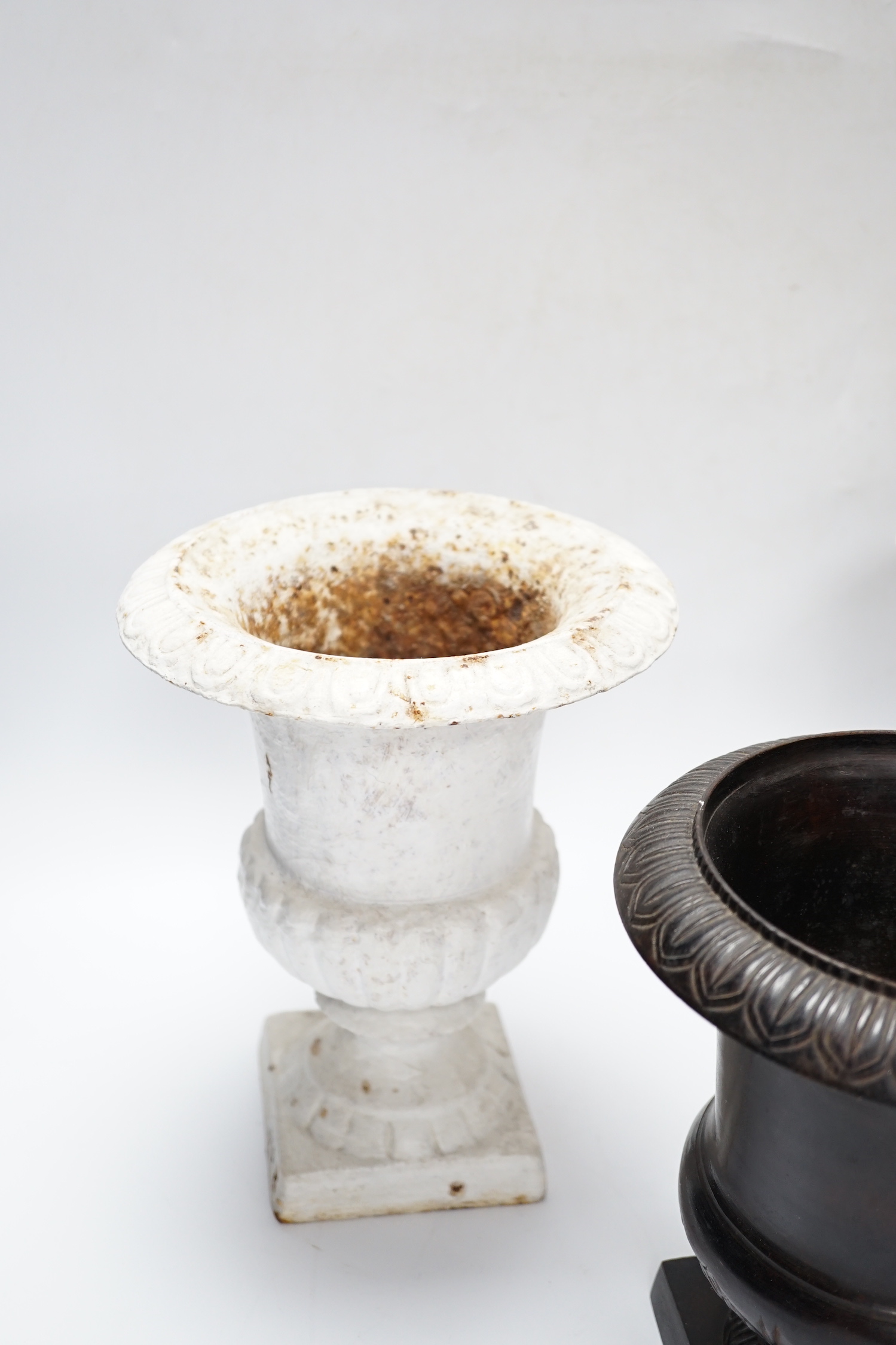 A pair of painted cast iron urns and another, tallest 23cm